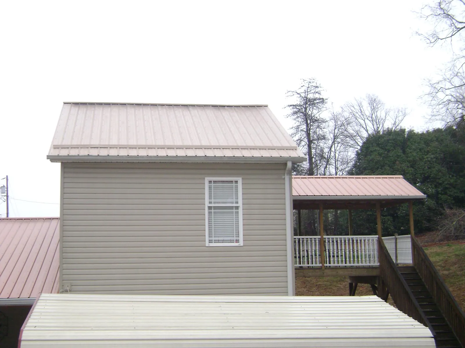 Tan metal roofs on a two story addition and attached porch, from a Roof Replacement job in Ewa Beach