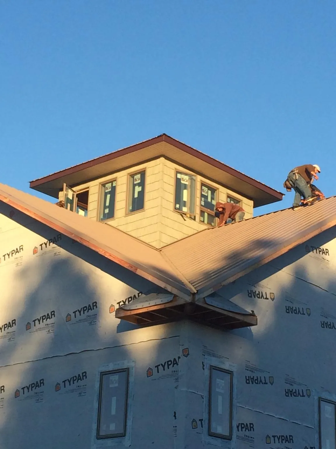 Roofers working around a rooftop cupola on a new metal roof at sunset — Roof Waterproofing in Ewa Beach by Roofing Brothers